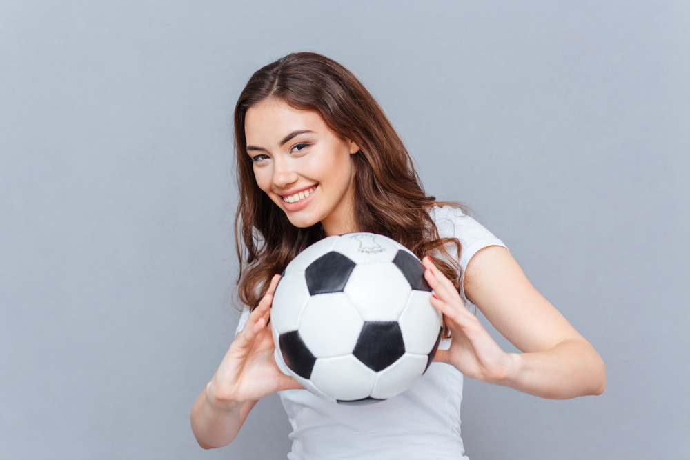 улыбающаяся девушка с футбольным мячом на поле