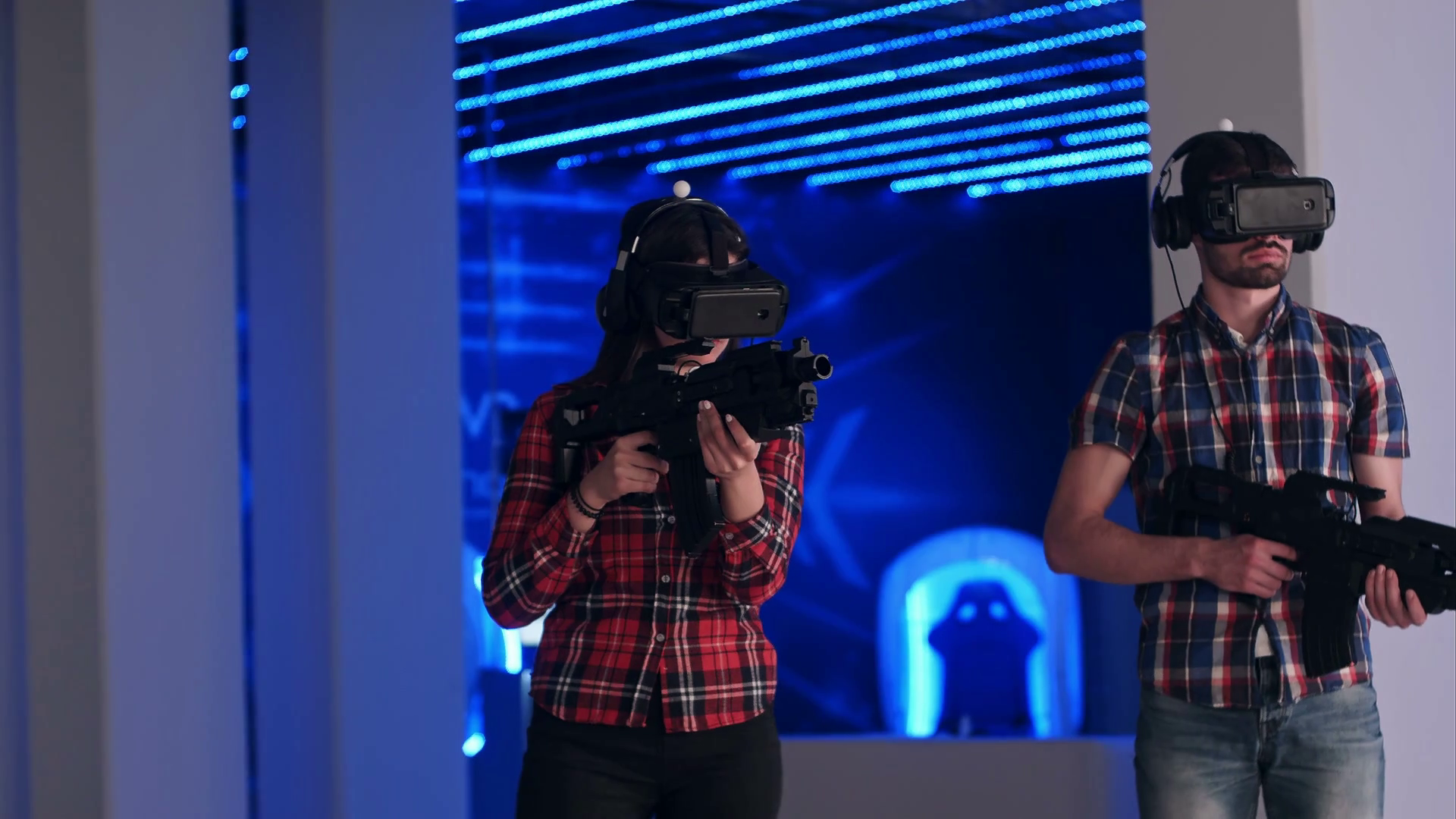 Young woman and man playing VR shooter game with virtual reality guns