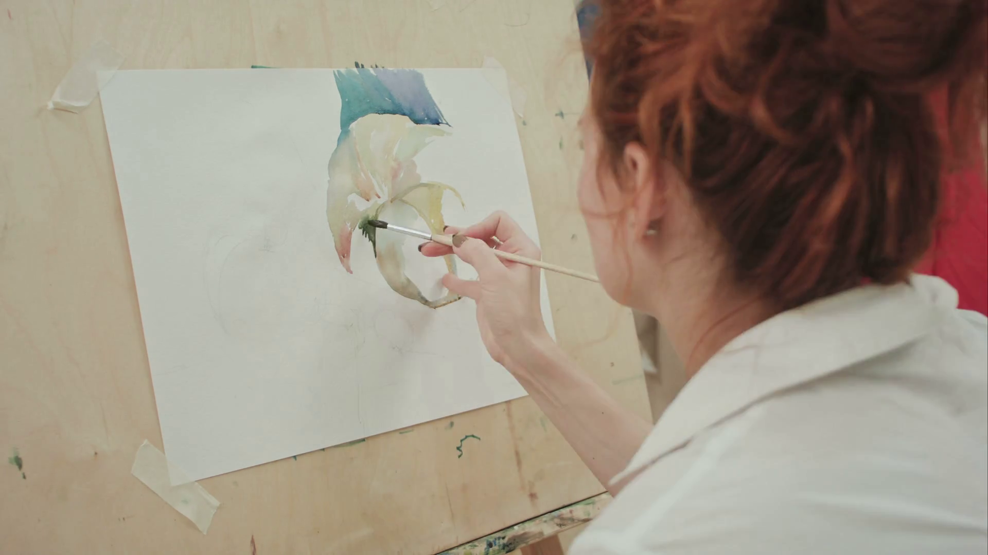 Woman artist painting a picture in studio while talking on the phone