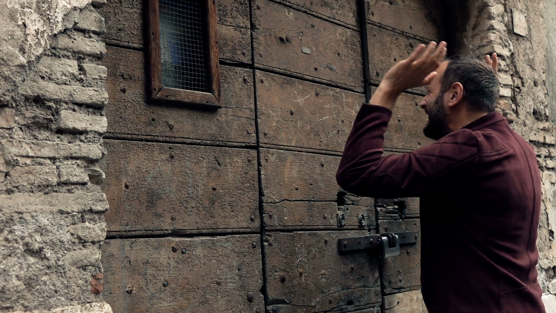 Angry man knocking on wooden, old entrance door, super slow motion