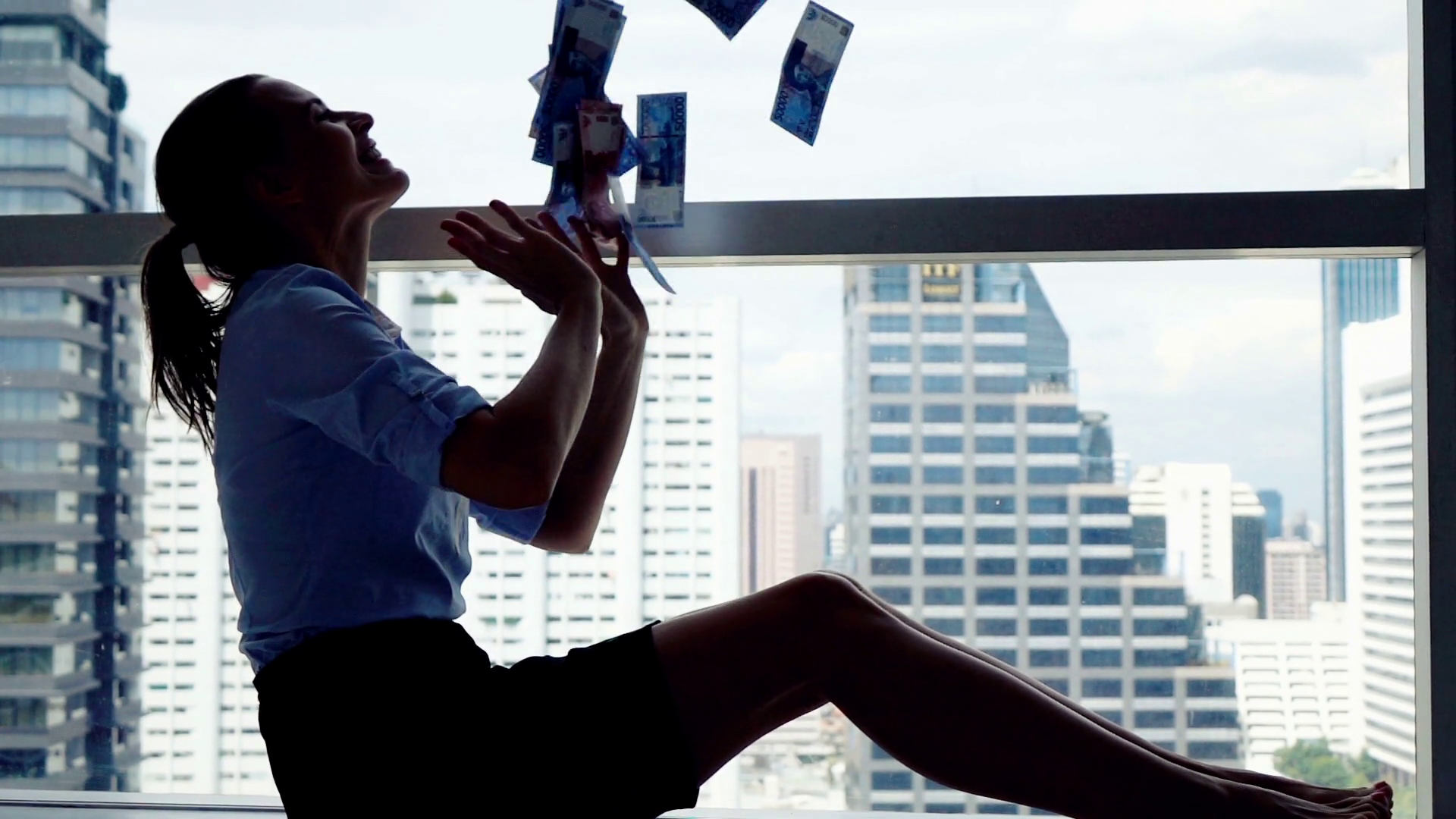 Happy businesswoman throwing money sitting by window in the office, super slow motion Stock