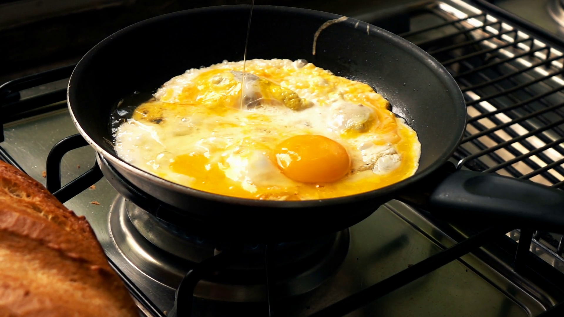Pouring eggs on frying pan in the kitchen, super slow motion Stock