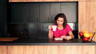 Graceful woman enjoying a book in the kitchen