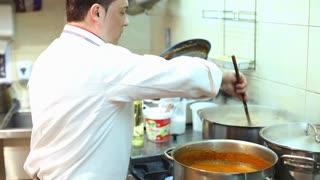 Chef cooking stirring pot in kitchen