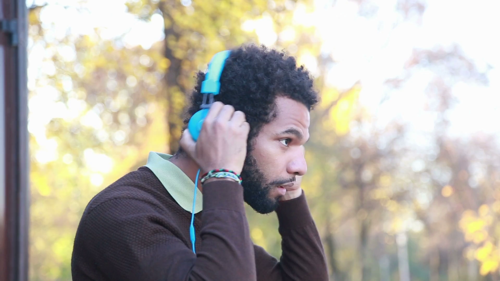 Profile of man putting on headphones and listening to music in nature
