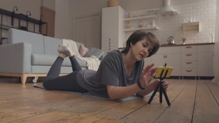 Woman Surfing the Top Online Fitness App on her Phone. Woman lays on the mat and searches for the best home fitness training ever.