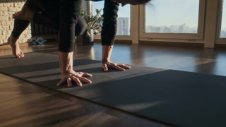 Focused man plants hands on yoga mat near tall studio window