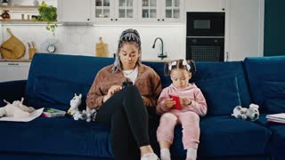 Lack of real communication in society. Young african american mother and her little daughter web surfing on smartphones