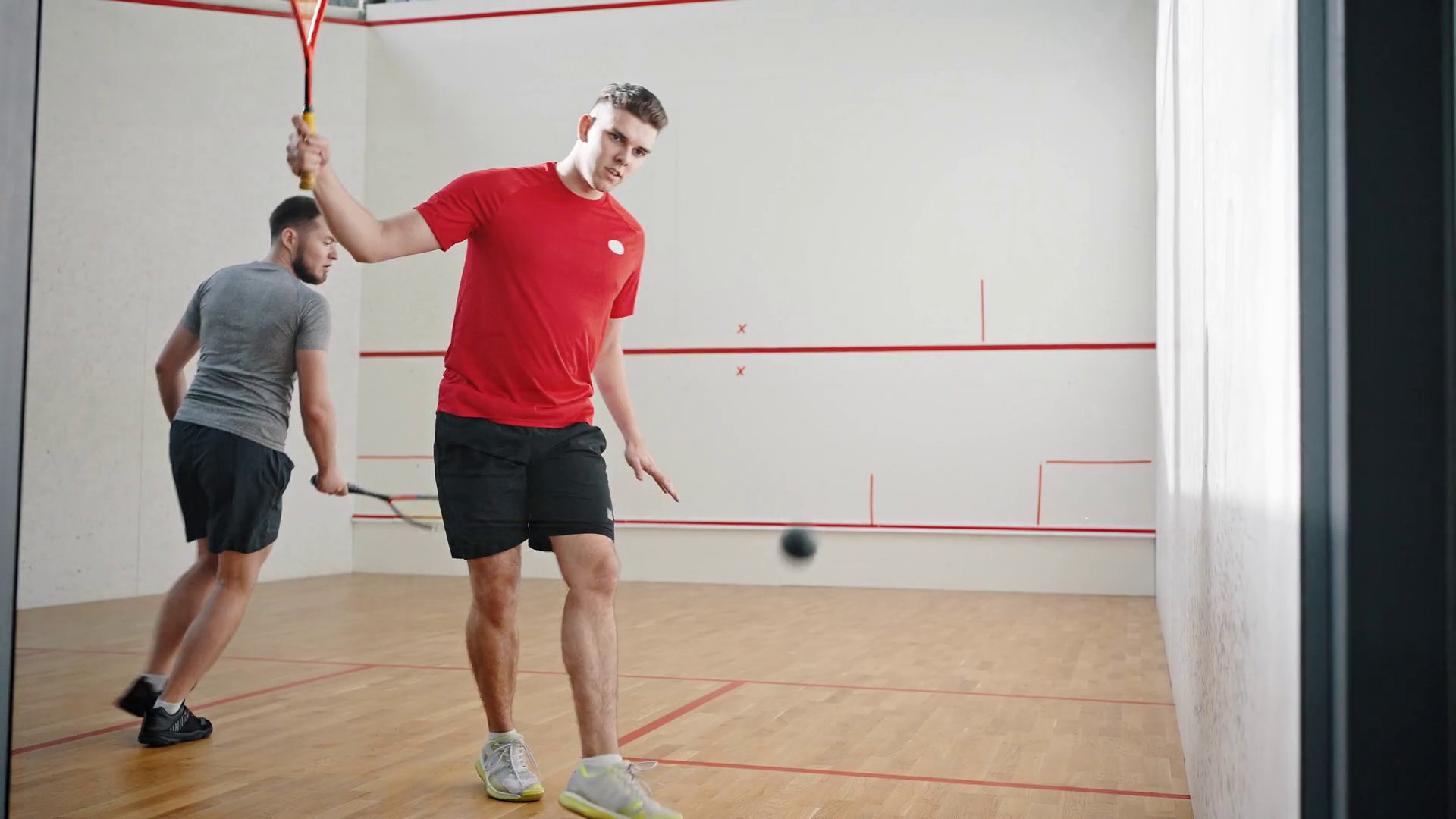 Couple of athletes plays squash in light court energetically Stock