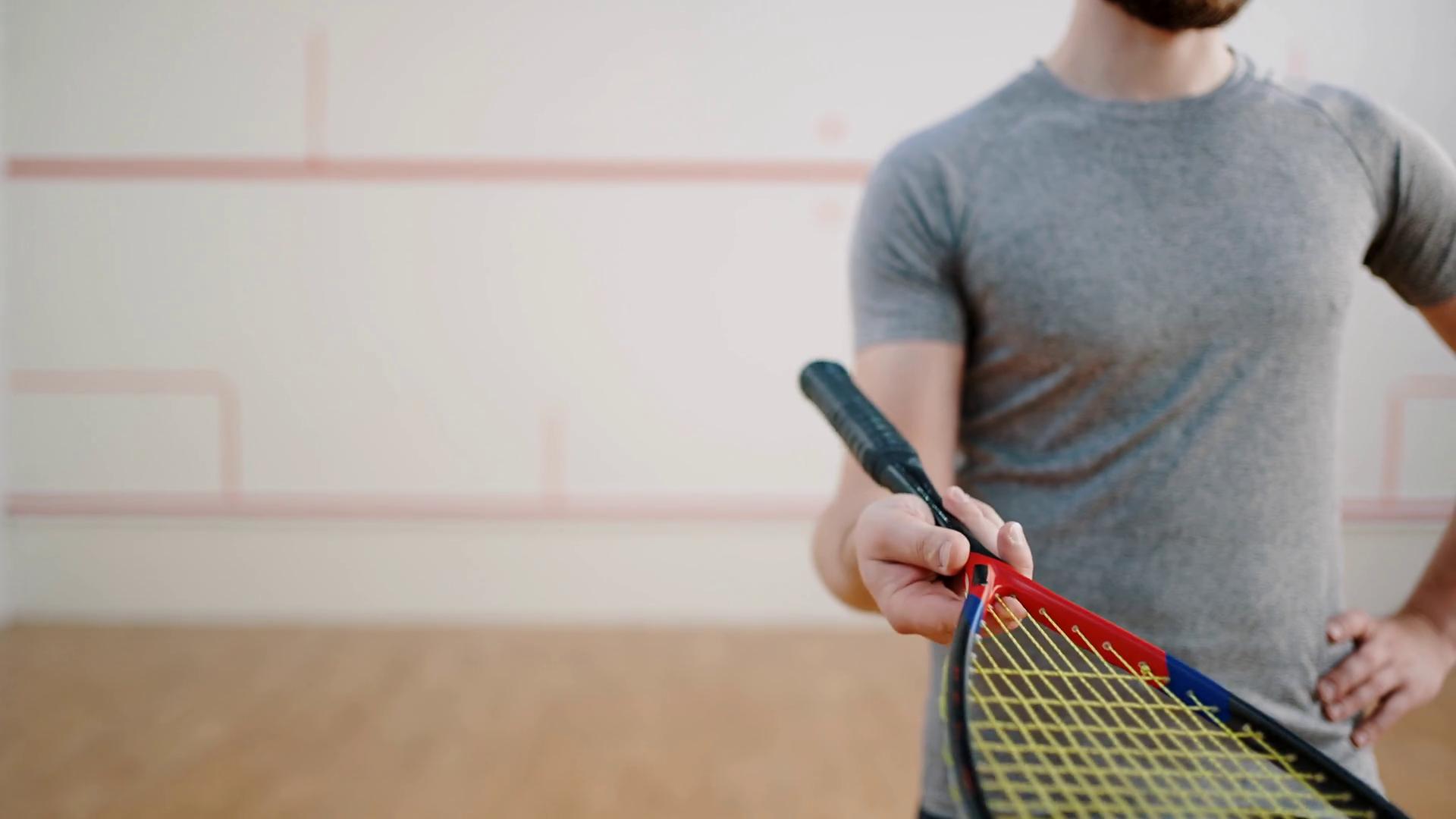 Sportsman stands in squash court spinning racket on finger Stock Video