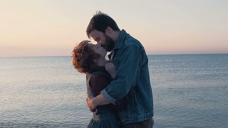 happy loving couple kissing on beach during sunrise or sunset, 4k