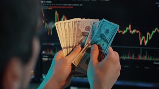 Trader Counting Dollars in Front of Charts