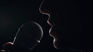 Male Mouth Singing into Microphone on Dark Stage Under Spotlight