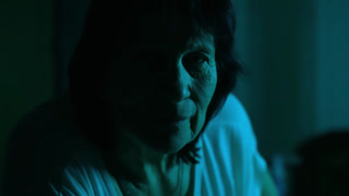 Creepy old woman smiling in darkness staring intently