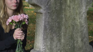 Girl attending funeral with pink flowers at cemetery 4k