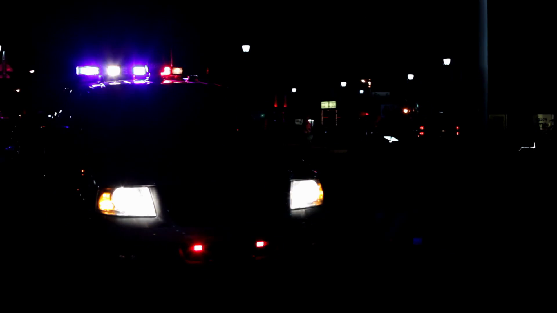 Police car flashing lights while people walk by at night Stock Video