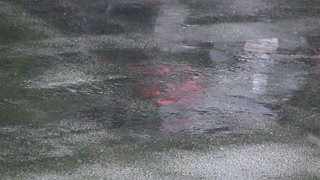 Rain from passing storm landing on pavement in slow motion