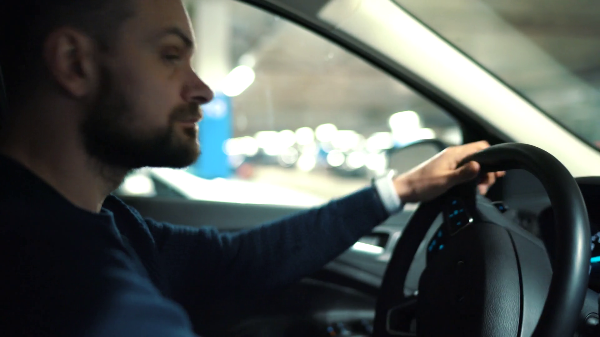 Man is driving through a parking lot and is looking for a place to park