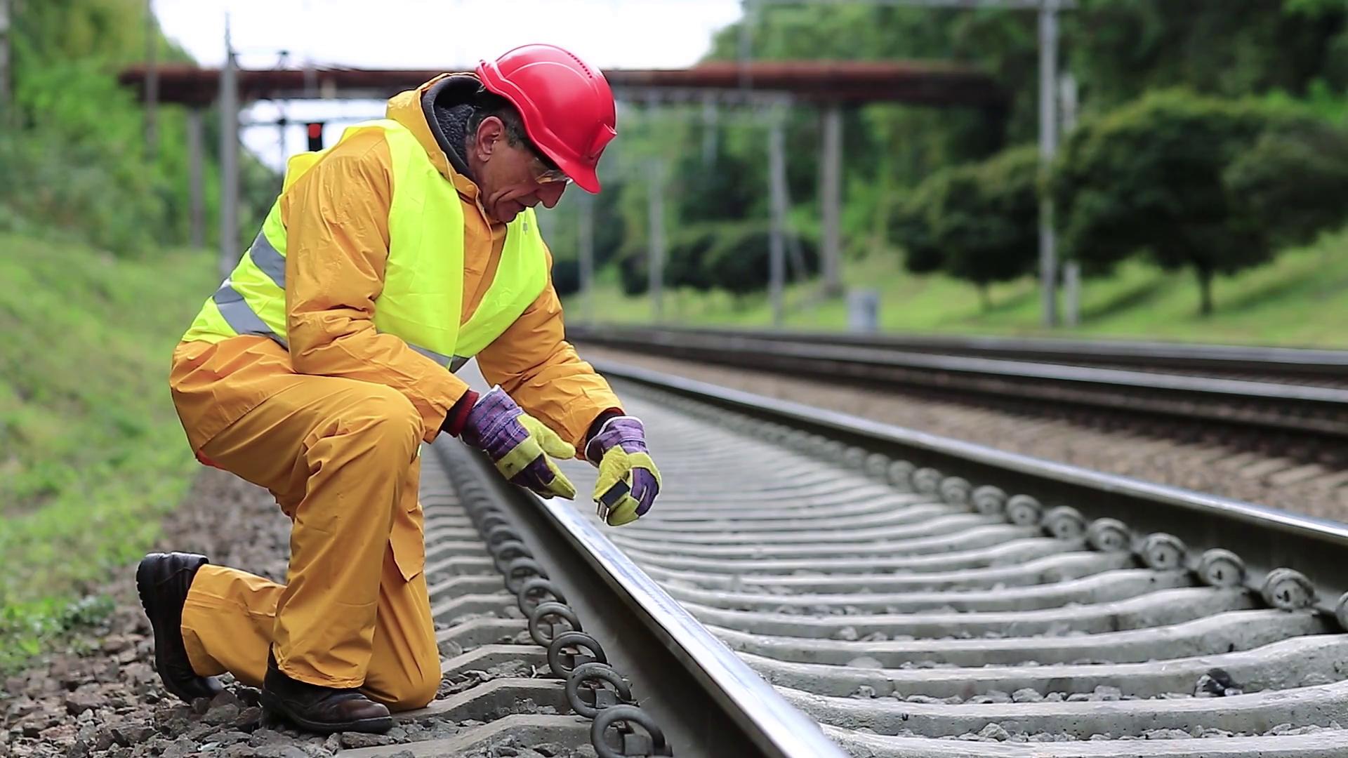 Railway worker in yellow uniform with level measuring instrument on