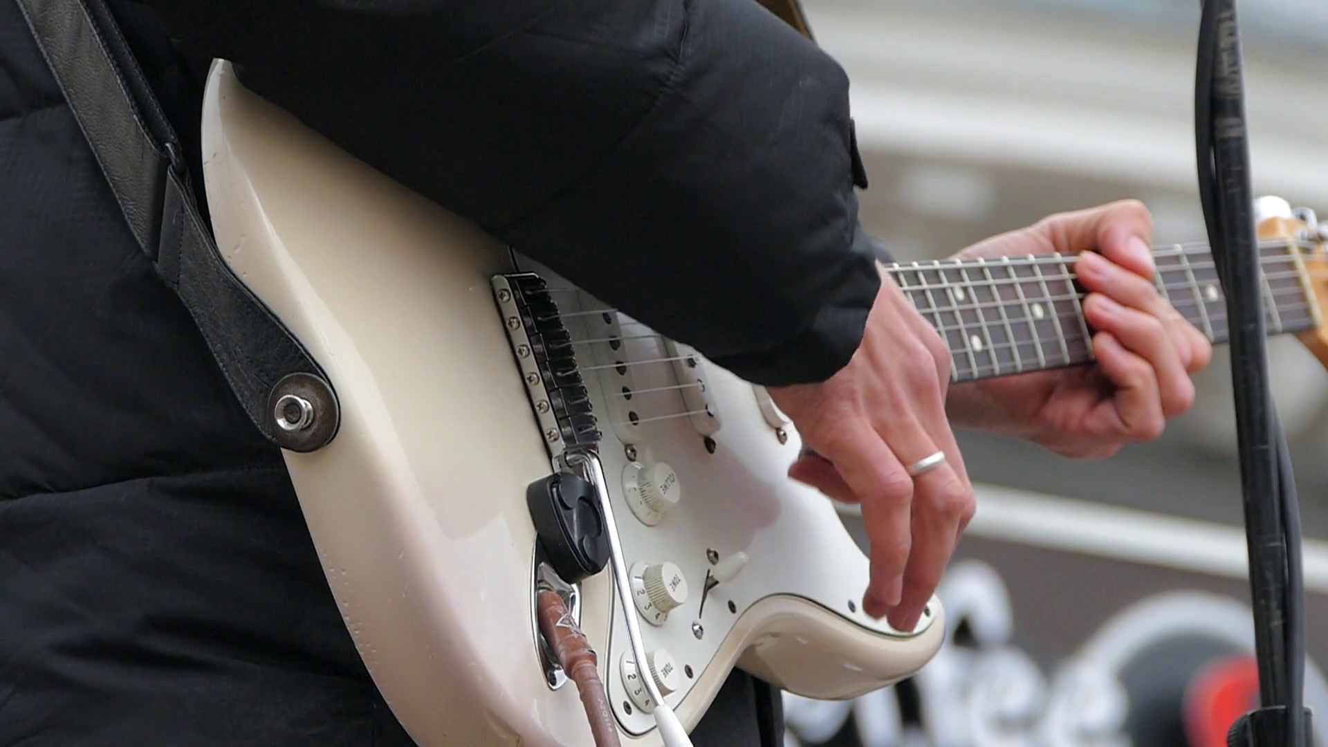 A man plays on electric guitar strings with a white body using a mediator. Slow motion. Stock