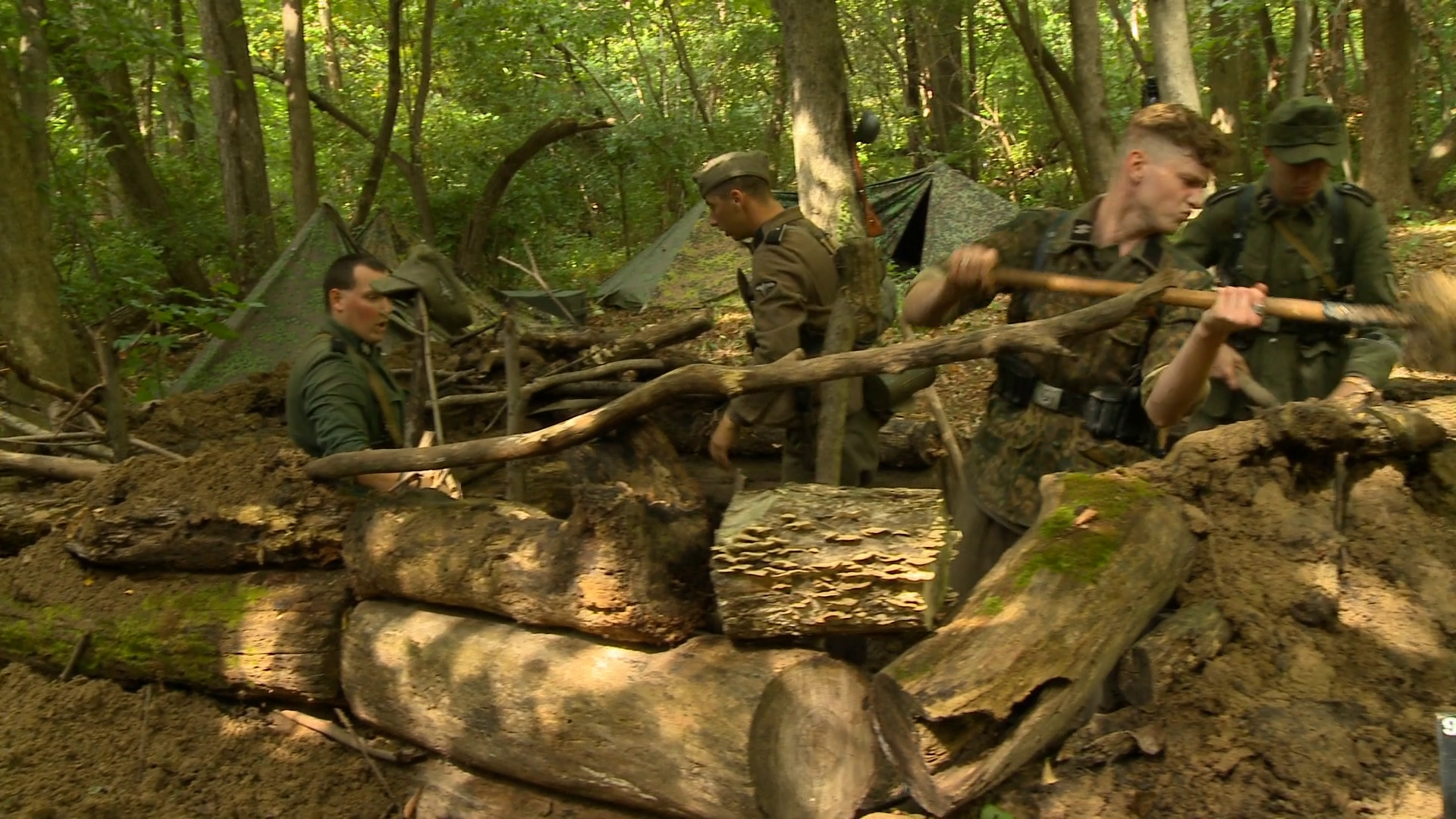 Young German soldiers in World War II dig a foxhole in the forest. They