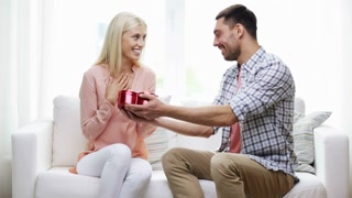 relationships, love, people, valentines day and holidays concept - man giving woman red heart shaped gift box