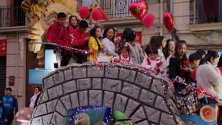 VALENCIA, SPAIN JANUARY 29, 2025: Smiling chinese people waving from a decorated float during Chinese New Year parade in Valencia, Spain