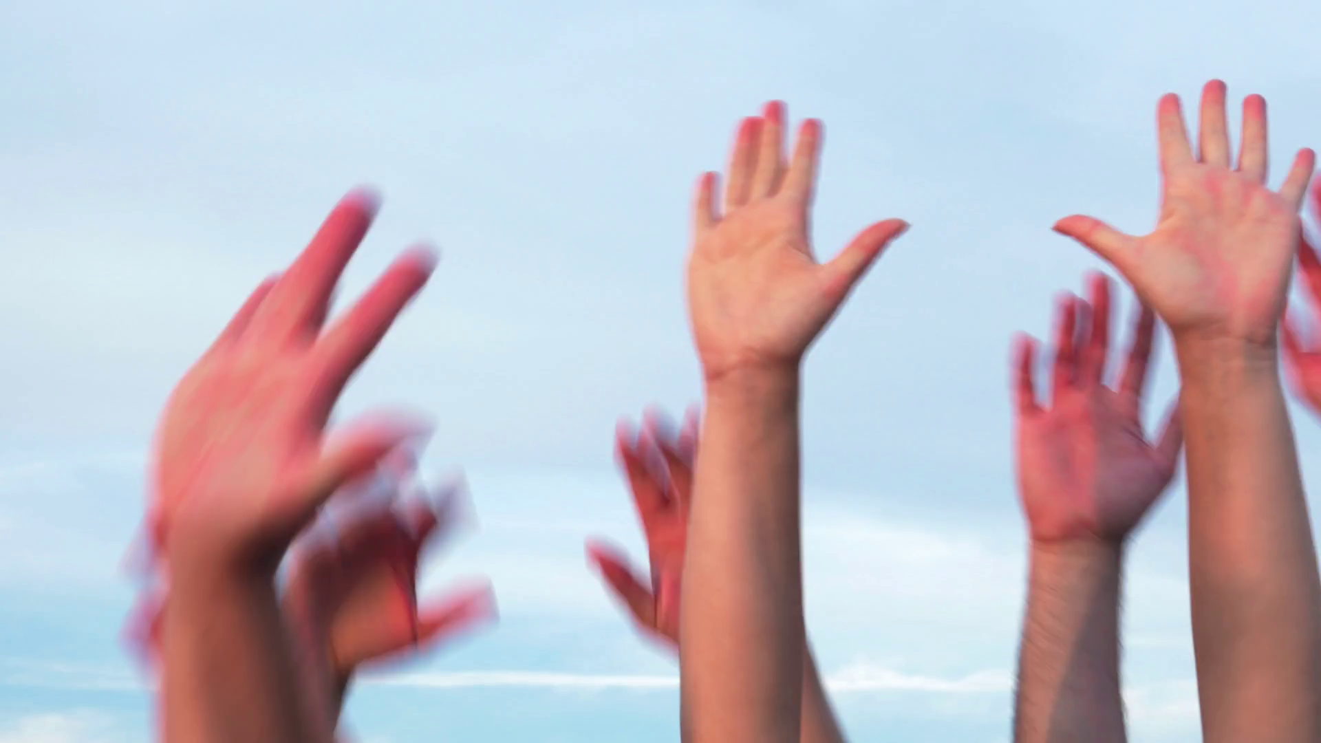 Several people raising hands up in the air against of blue sky Stock