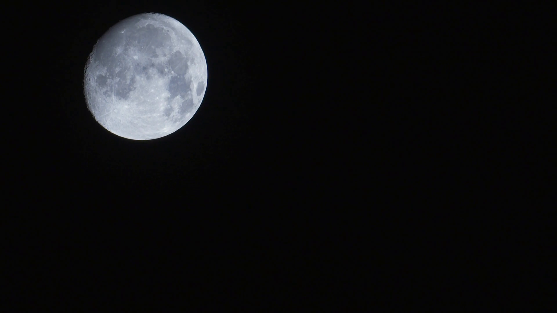 Timelapse of a setting near full moon, moving across a black night sky