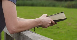 Woman reading the Bible, closes it and walks away.