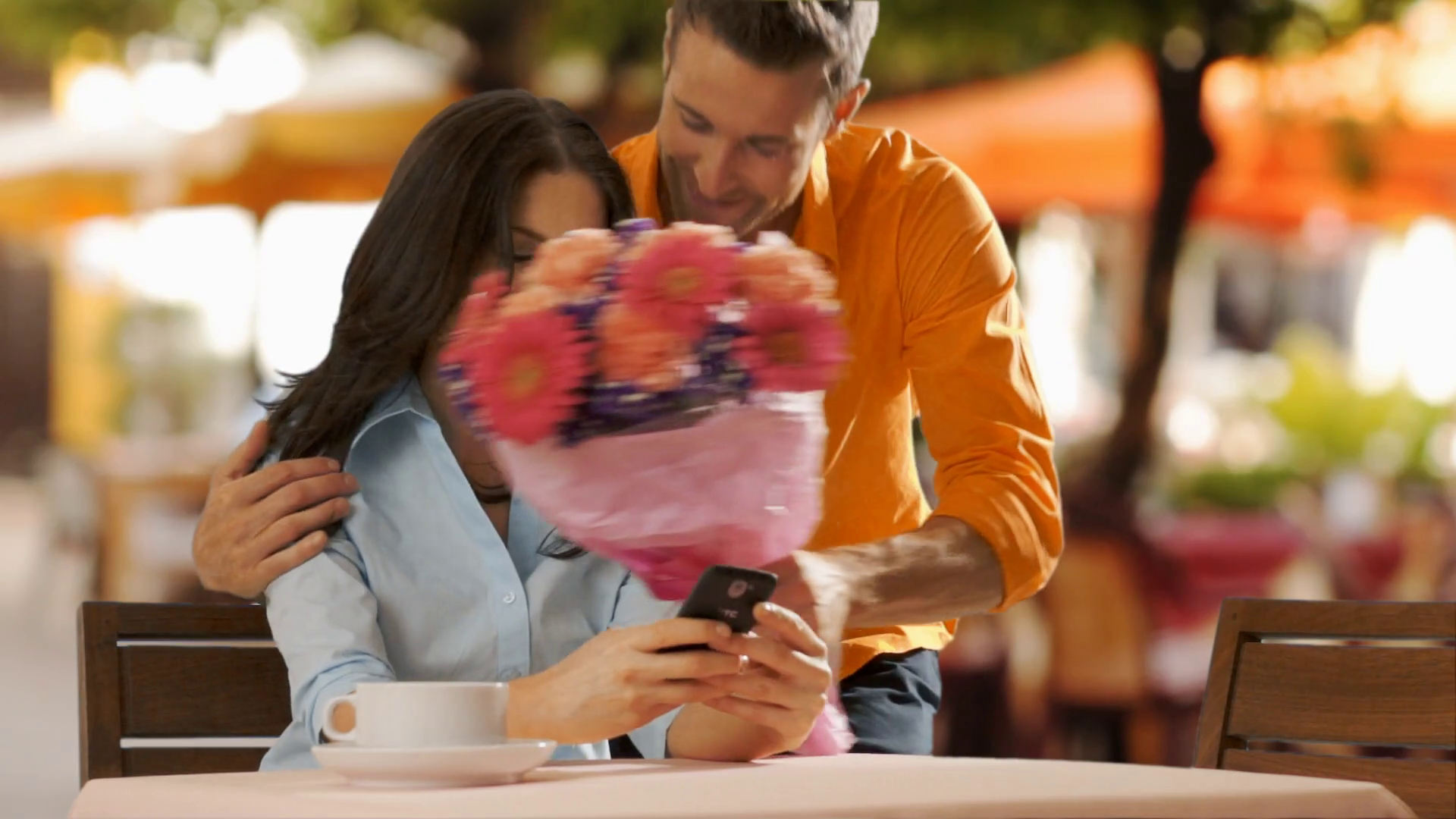 Young man bringing flowers to young woman in cafe. Stock Video Footage