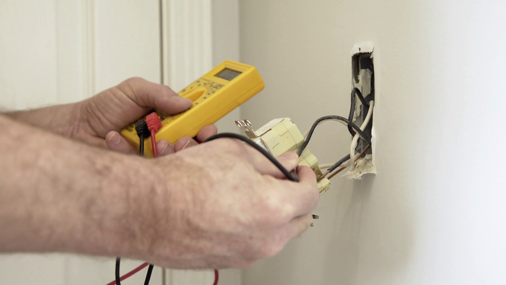 electrician checking voltage on a ground fault outlet wide 4k Stock