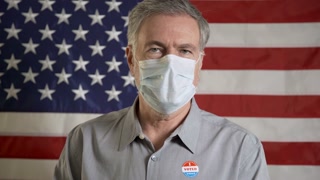 man with a mask during covid in front of an american flag just voted