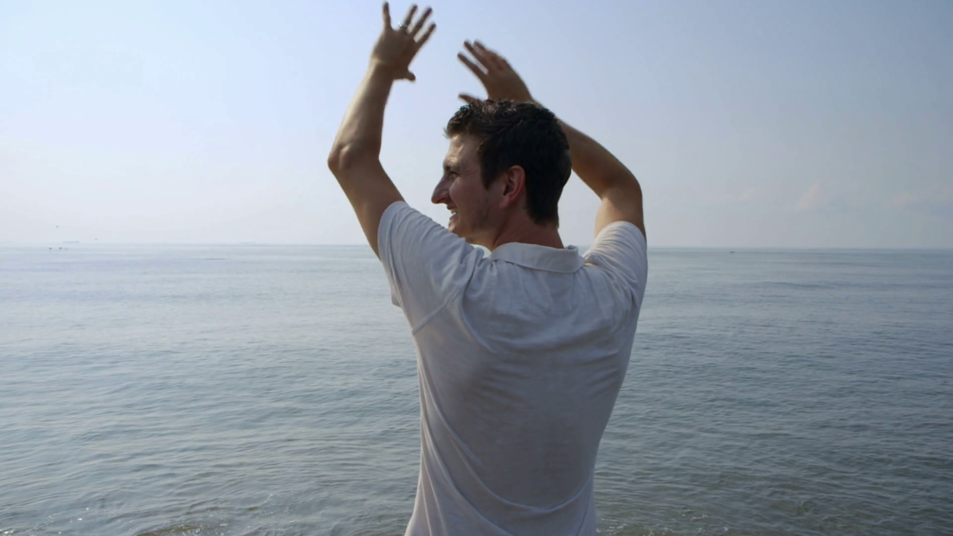 Young Man Holding Arms Up Enjoying Ocean Stock Footage SBV300273187
