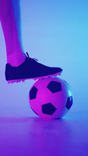 Close-up shots of a football player with soccer cleats controlling a classic black and white soccer ball on a smooth surface illuminated by
