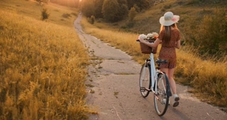 A girl in a hat with a Bicycle turns around and looks at the camera smiling.
