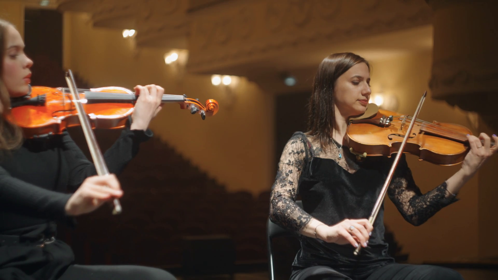 women violinists are playing music on scene of music hall, professional musicians in