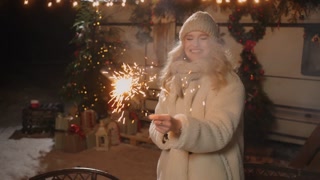 woman with sparkler smiling and looking at camera, Christmas congratulation, celebration