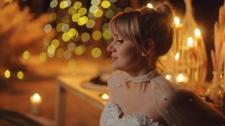 Portrait Of Beautiful Dreamy Bride On Sandy Beach In Night, Romantic Decoration With Burning Candles