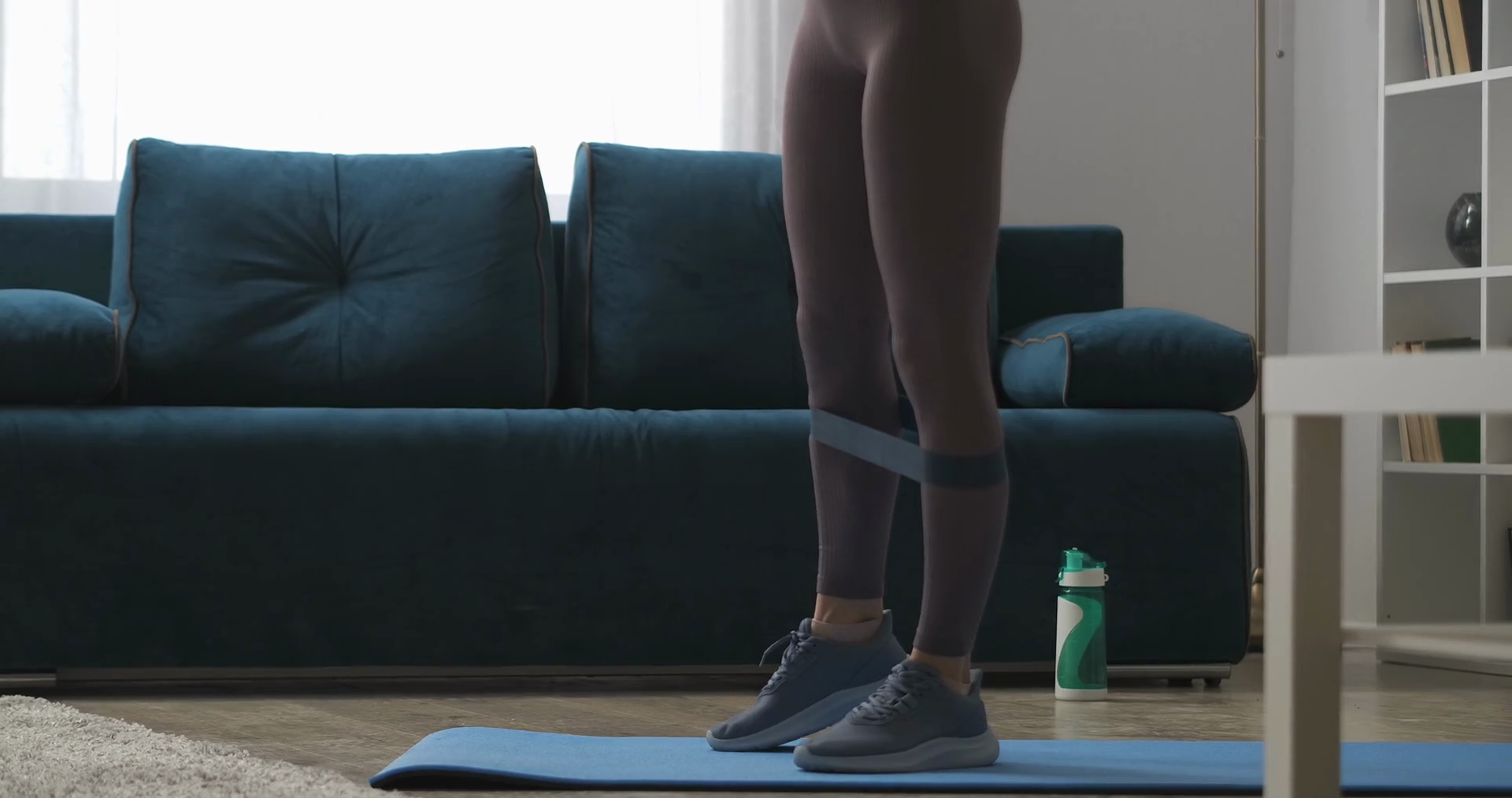 home fitness, woman is training legs with sporty elastic band, tensing