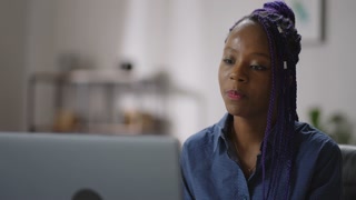portrait of black businesswoman talking by online video call in laptop in home office, looking at web camera and chatting, online business meeting or webinar