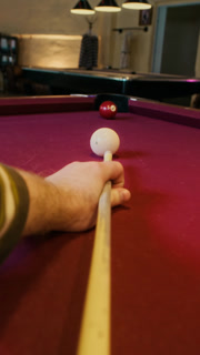 Vertical POV shot of unrecognizable man lining up shot on red felt billiard table then successfully sinking ball while playing pool in snooker hall