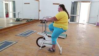 overweight woman exercising on bike simulator