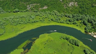 Aerial view of Rijeka Crnojevica - boats on beautiful river between mountains flowing into Skadar Lake, Montenegro, 4k