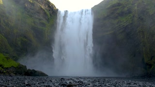 Majestic Skogafoss waterfall pours over rugged cliffs, creating a stunning natural display. Surrounded by lush greenery, the powerful water