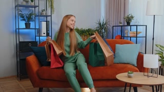 Happy teen girl shopaholic consumer came back home after online shopping sale with bags at home