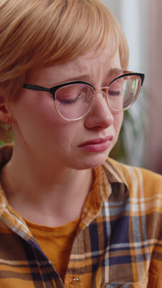 Vertical close up view of Upset disappointed young blonde woman wipes tears and cries from despair at home