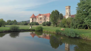 Bride and Groom Walking Close to the Lake and a Castle