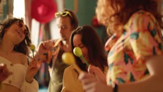 Joyful friends dancing with maracas, having a party in the cafe