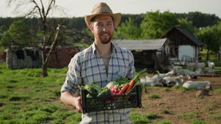 Cheerful farmer holding basket with vegetables and looking at camera